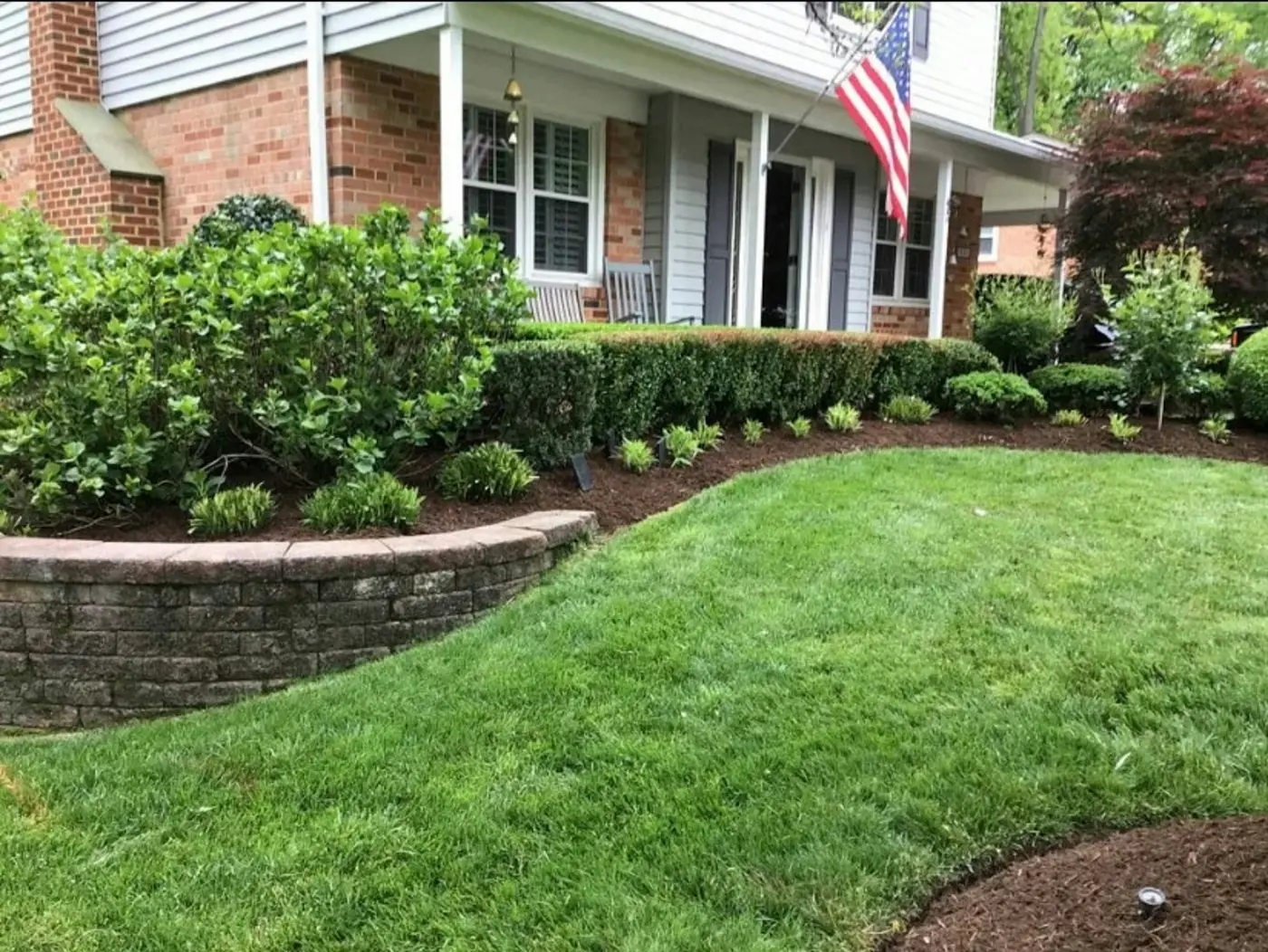 A freshly mowed front lawn with trimmed shrubs and new mulch beds